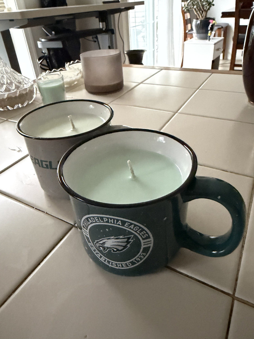 Deep green Philadelphia Eagles mug candle in front of the cream Eagles mug candle