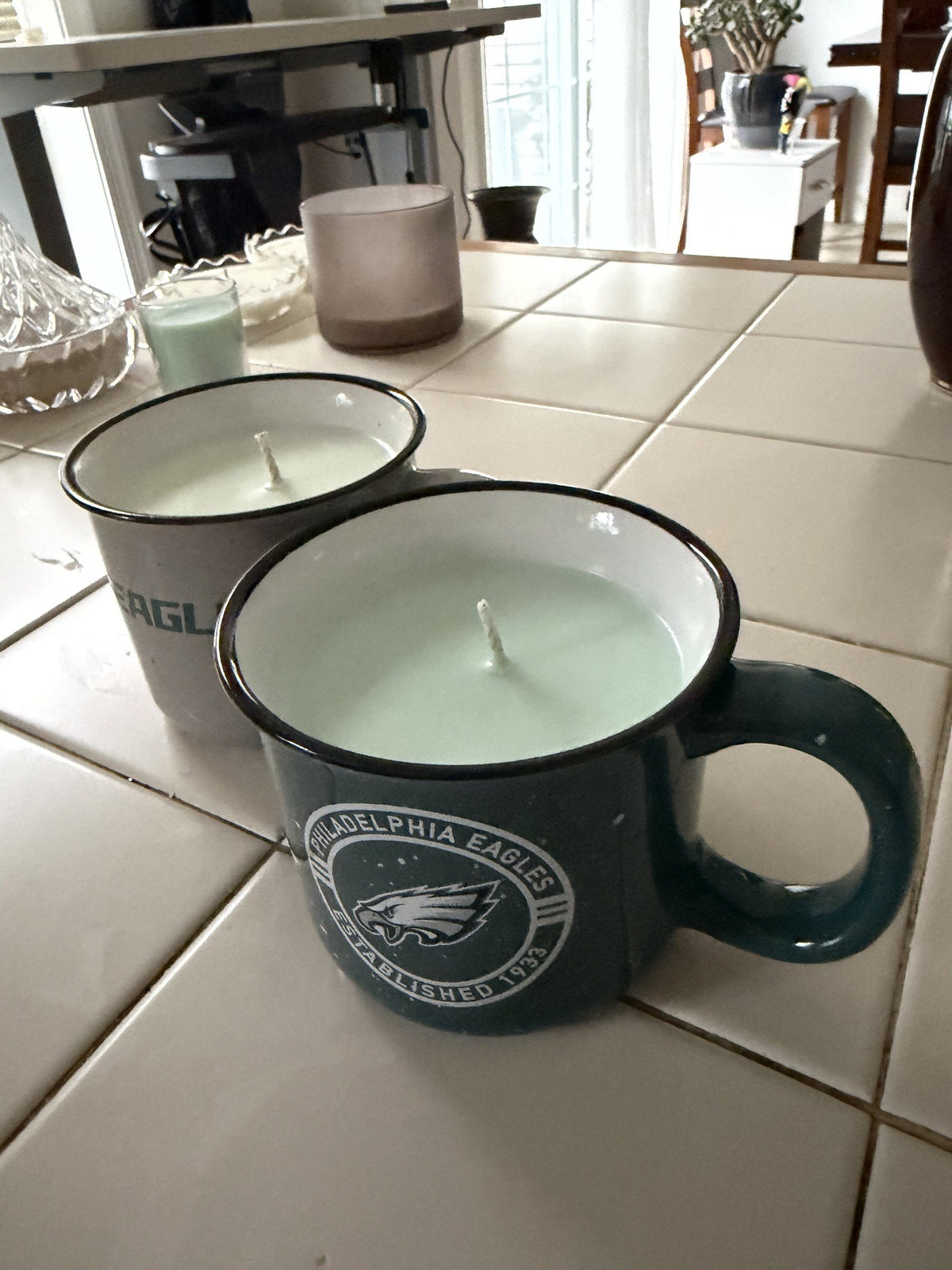 Deep green Philadelphia Eagles mug candle in front of the cream Eagles mug candle