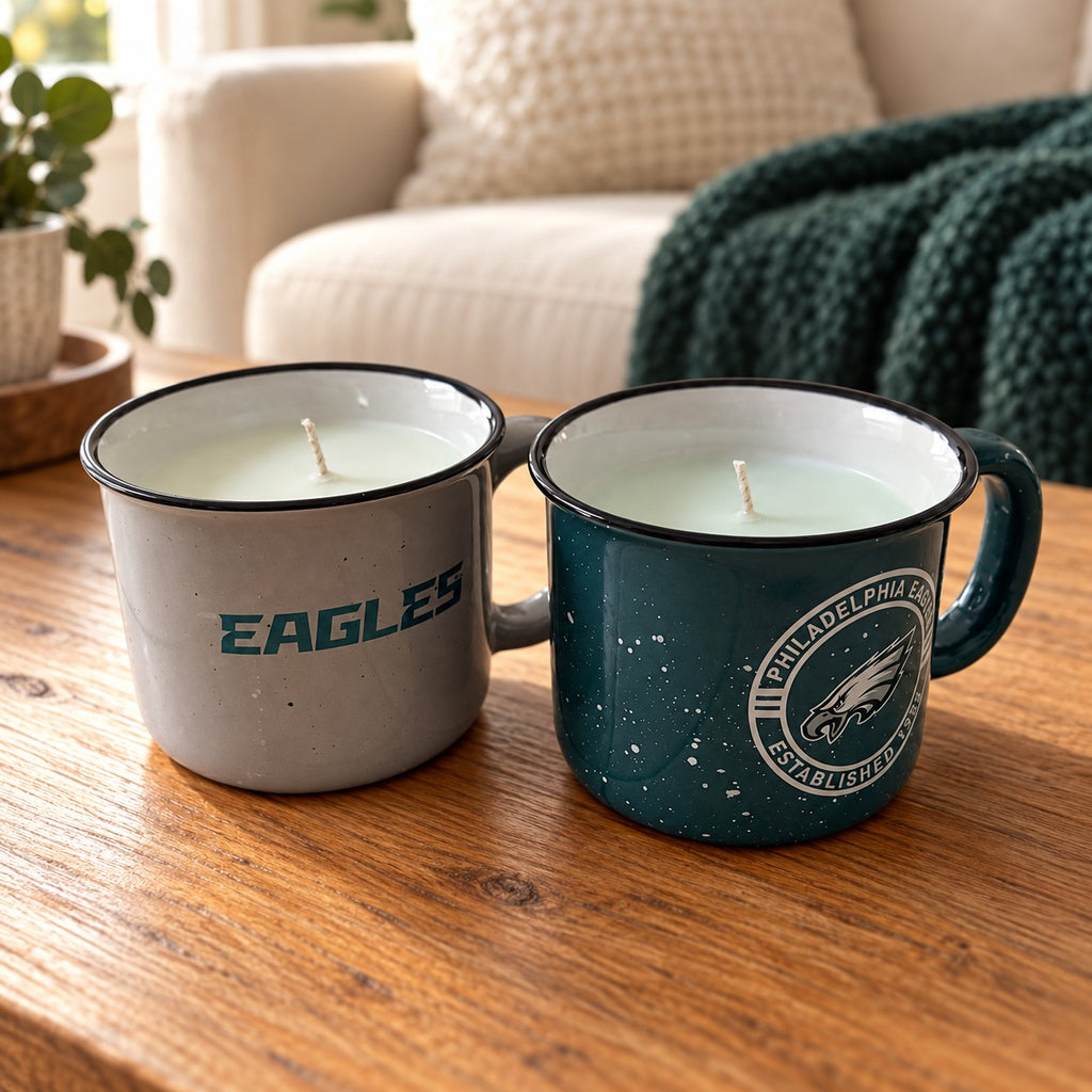 Cream and deep green Eagles mug soy candles side by side on a wood table, sold together as a two-candle set.