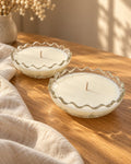 Two matching Honey & Home candles in clear ruffled glass bowls