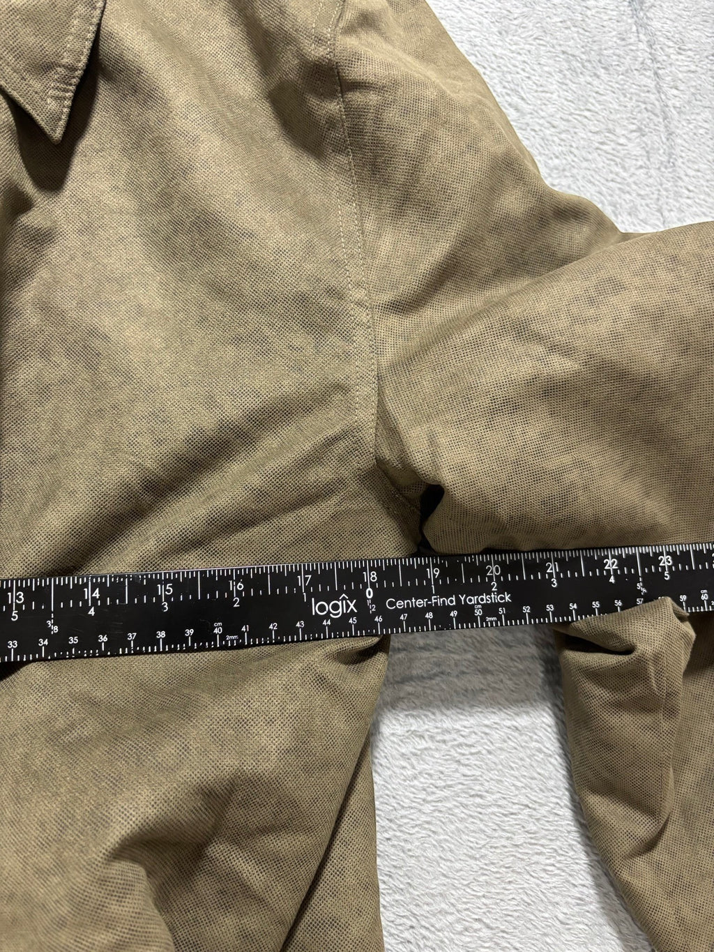 My Second Story Vintage & Black olive field jacket sleeve measurement with a yardstick showing size details.