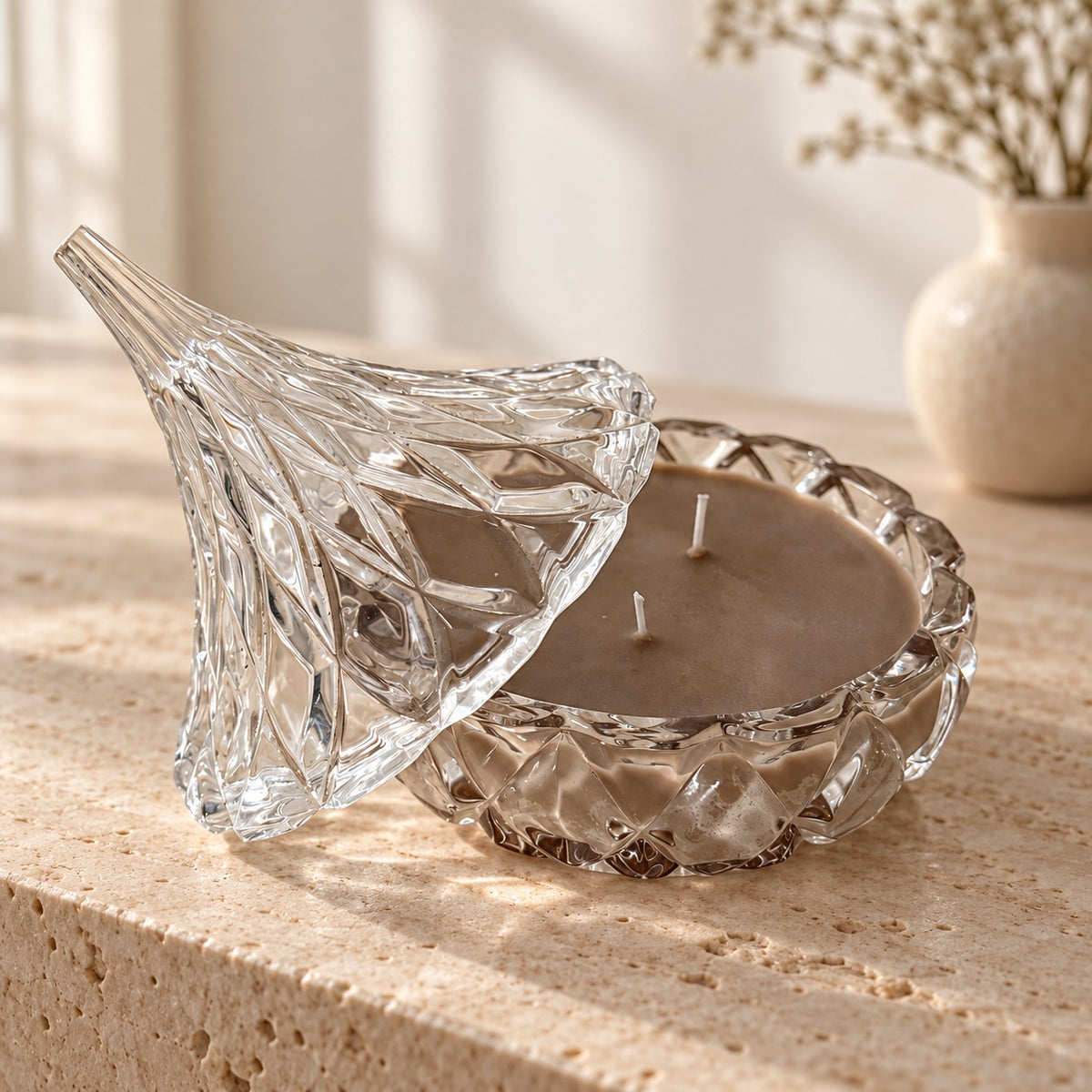 Sealed With a Kiss brown soy candle in a clear cut-glass dish with its pointed glass lid tilted beside it.
